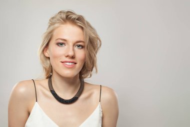 Açık tenli, yumuşak makyajlı, sağlıklı saçlı ve doğal duygusal yüz ifadesi olan arkadaş canlısı genç bir bayan model. Beyaz arka planda sarışın kadın.