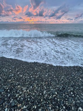 Deniz sahilinde gün batımı. Bulutlar ve güneş ışığıyla renkli günbatımı gökyüzü. Gün doğumu arkaplanı
