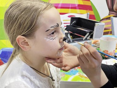 Esmer kız yaratıcı karnaval makyajı yaptırırken bekliyor.