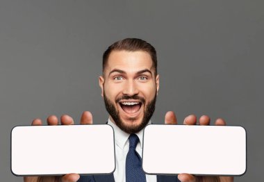 Mutluluktan haykıran etkileyici başarıları olan genç ve mutlu bir iş adamı. Erkek yüzü iki boş telefon ekranı ile kapanıyor.