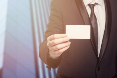 Beyaz kartvizit tutan takım elbiseli bir adam. Profesyonellik ve resmiyet kavramı