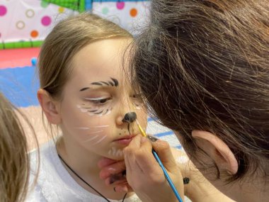 Makyaj sanatçısı yaratıcı karnaval makyajını yaparken güzel bir kız bekliyor. 