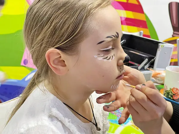 Esmer kız kreatif makyaj yaptırırken bekliyor.