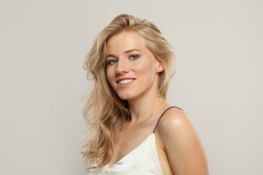 Sevimli gülüşü olan neşeli sarışın kadın kameraya bakıyor. Güzel genç yetişkin portresi.