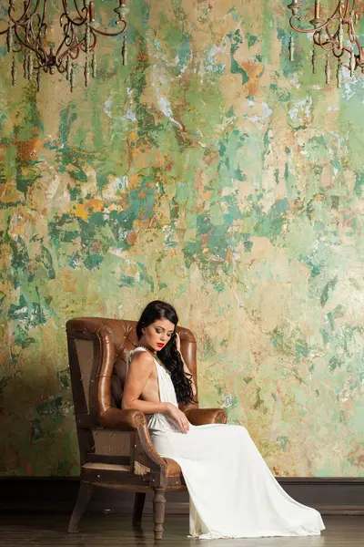 Uzun saçlı ve makyajlı mükemmel bir kadın lüks bir iç mekanda oturuyor.