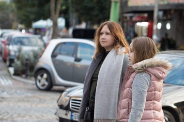 Anne ve kızın dış portresi. Birbirlerinin elini tut ve yaya geçidinden karşıya geç.