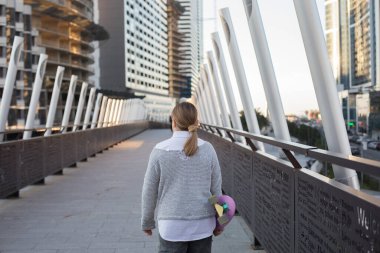 Dışarıda yürüyen kaykaylı küçük bir çocuk.