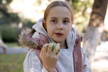Dışarıda elma yiyen sevimli bir çocuk. Genç kız 10 yaşında.