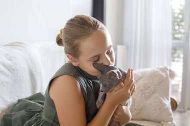 Sevecen bir genç kız evde kedisine sarılıyor..