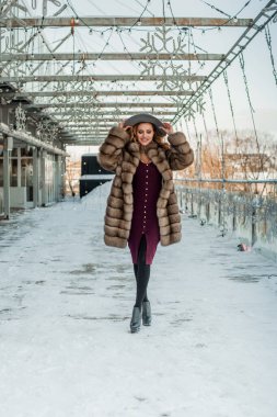 Kar Şehri caddesinde şapkası ve kürkü olan çekici esmer kadın..