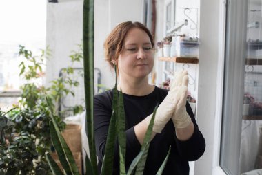 Kapalı alanda zımparalanırken eline nitril eldiven takan neşeli bir kadın. Bahçe işleri, rahatlama ve ekme konsepti.