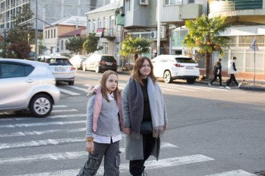Güzel anne ve kız birbirlerinin elini tutup yaya geçidinden karşıya geçiyorlar..