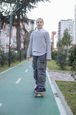 Pembe kaykaylı mutlu kız çocuğu. Kaykay yetenekleri.