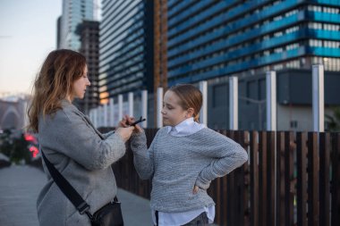 Kadın ve küçük kız şehrin sokaklarında yürüyorlar. Çocukluk, mutluluk, tatil, aile ve eğlence etkinliği kavramı.