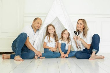 Evde yavru köpek evcil hayvanıyla eğlenen mutlu bir aile portresi. Baba, anne ve iki kız.