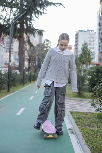 Dışarıda kaykayla gezen neşeli genç bir kız çocuğu.