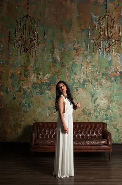 Şık genç bayan model esmer. Kapalı alanda kameraya bakıyor. Tam boy portre.