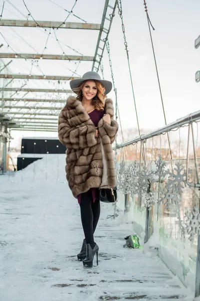 Kırmızı elbise ve kürk kürk manto giyen çekici esmer kadın. 