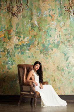 Yeşil arka planda şık giyinen neşeli, sağlıklı bir kadın..