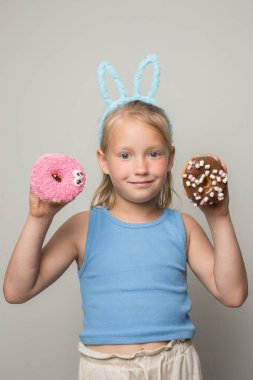 Sevimli kız, asabi donut tutuyor. Küçük tatlı bir kız tatlı yemekler yiyor.