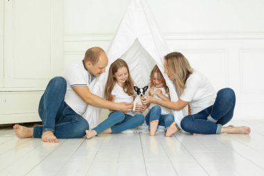 Gülümseyen aile evde köpek yavrusuyla eğleniyor.