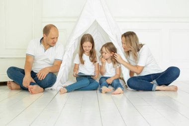 Evde tablet kullanan sevimli bir aile. Baba, anne ve iki kız.