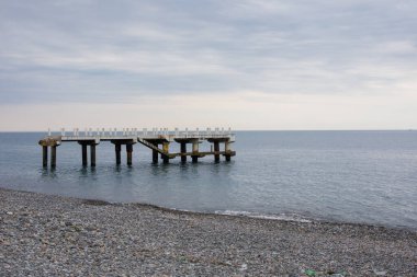 Terk Edilmiş İskele Deniz suyunda Gün batımında Rocky Sahili 'nde