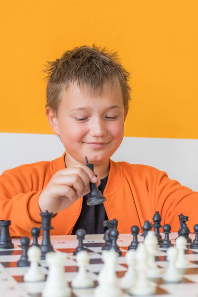 Счастливый школьник играет в шахматы в классе. Ребенок с шахматами
