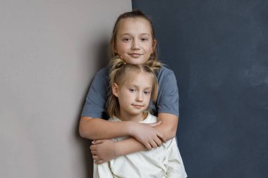 Çekici kardeş çocuklar evde eğlenirken mavi ve beyaz arka planda duruyorlar. Küçük kız 6 yaşında ve oğlan 11 yaşında.