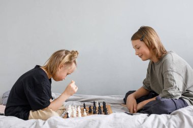 Gülümseyen oğlan ve kız satranç oynarken bilgiyle, stratejiyle hareket etmeyi ve evde gelişim ve büyüme için kazanmayı planlıyorlar.