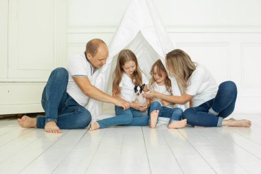 Şirin bir aile evde köpek yavrusuyla eğleniyor.