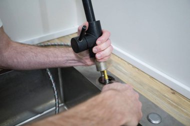 Mutfak musluğunu tamir eden muslukçunun ellerini kapat.