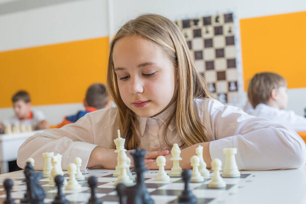 Привлекательный школьник на уроке шахмат в школе. Портрет умной девочки