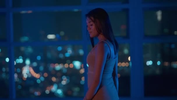 背の高い窓の前を歩く若い女性とマニラの街の屋上夜景をお楽しみください 中スローモーション Bokeh Shot — ストック動画