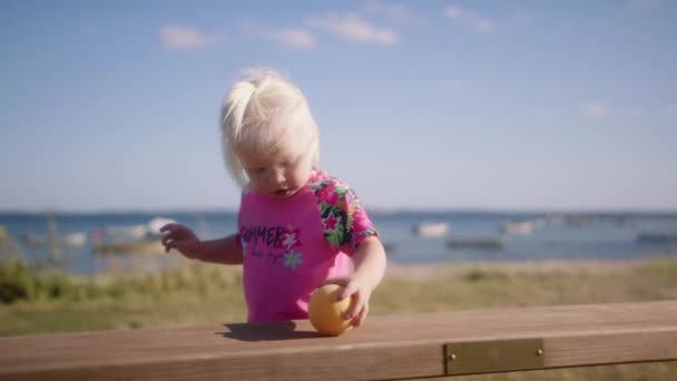 Klein Meisje Roze Bloemenhemd Kijkend Naar Camera Schuivend Een Oranje — Stockvideo