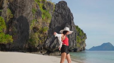 Güneşin sıcaklığını hisseden, kollarını kaldırmış Elantula sahilinin güneşli gününün tadını çıkaran bir kadın.