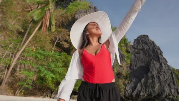 太陽の方を見ながら彼女の目を覆うエンタルーラビーチの女性のワイドショット — ストック動画