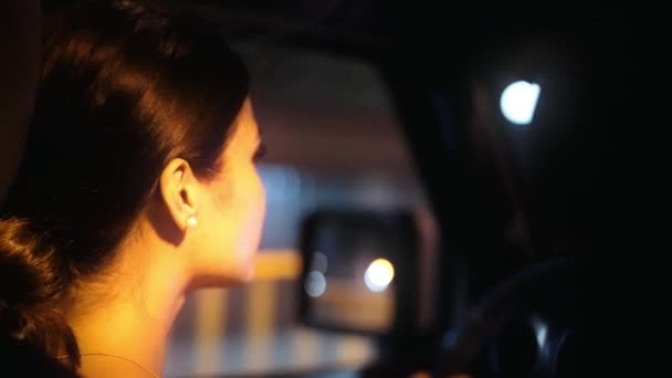 ブルネットの女性ドライバーは夜に街の道を慎重にナビゲートします — ストック動画