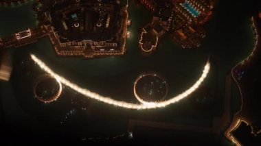 Dubai çeşmesinin sıcak ışıklarıyla su ekranının havadan çekilmiş bir görüntüsü.