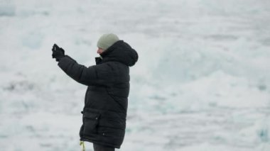 Adamın biri Ilulissat 'ın etrafındaki buzdağlarının videosunu çekiyor..