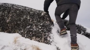 Ilulissat 'ta karlı bir günde kayanın üzerinden tırmanan bir adamın görüntüsü.