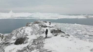 Ilulissat 'taki karlı bir dağın tepesindeki bir adamın yörünge görüntüsü.