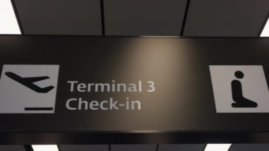 Dubai havaalanında farklı terminallerin yönlerini gösteren bir tabelanın görüntüsü.