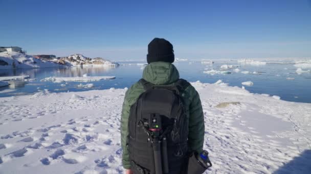 在Ilulissat 一个摄影师在白雪覆盖的海岸上行走的跟踪照片 — 图库视频影像