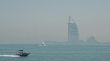 Burj Al Arab 'ın sisli görüntüsüyle denizi geçen bir sürat teknesi.