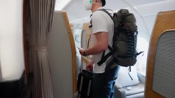 Man Backpack Wearing Facemask Hat Looking His Plane Seat While — Stock Video