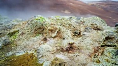 Buharlı ve bulanık arkaplanlı yosunlu kayaların yakın plan çekimi.