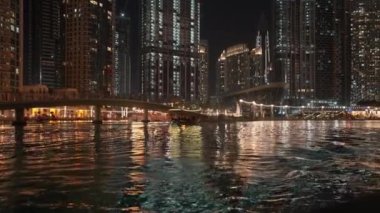 Güzel Dubai şehrini gösteren güzel bir gecede yolcularla dolu başka bir tekne manzaralı bir tekneden bir çekim..