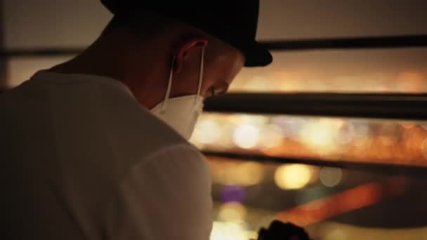 Ein Mann Mit Gesichtsmaske Und Hut Überprüft Den Bildschirm Seiner — Stockvideo