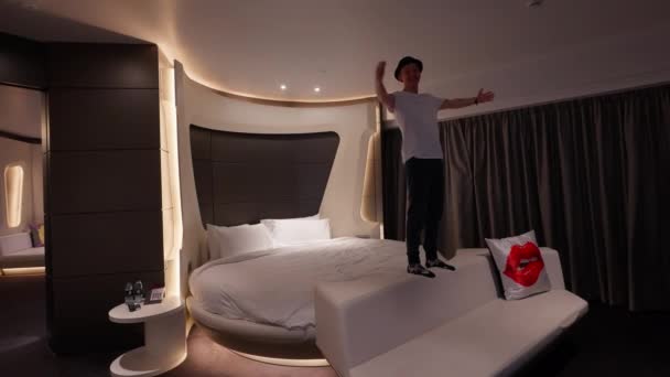 男はVホテルドバイの彼の部屋で快適な丸いベッドの上で休むように落ちます — ストック動画